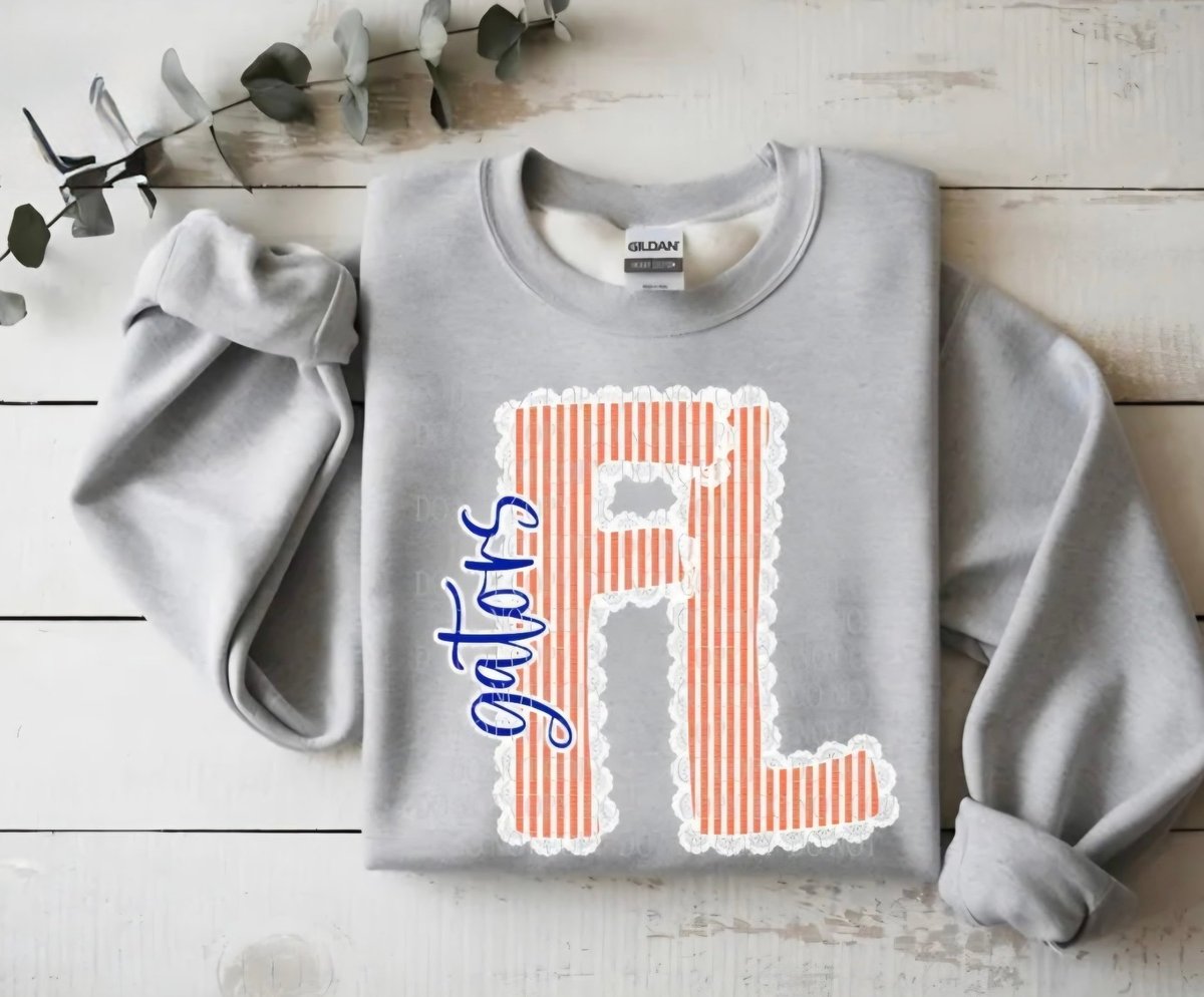 Light gray sweatshirt with red and white striped letter R and blue lights text on white wood